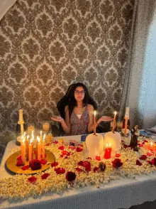 Mesa de ritual coberta de pipoca e rosas vermelhas, com velas acesas, velas em forma de cabeça e a imagem de Santo Antônio
